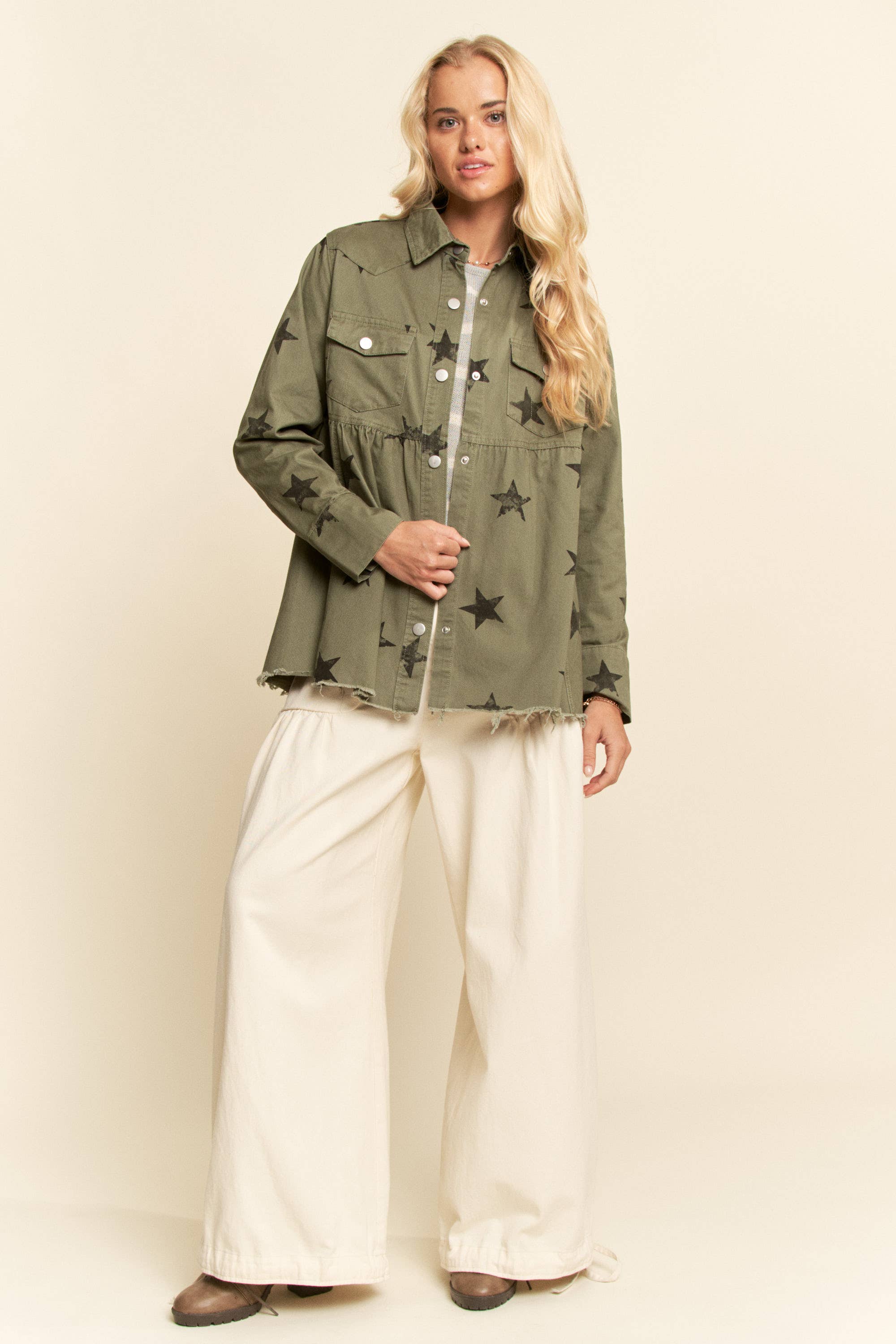 Olive star-print babydoll shacket with snap-button front, chest flap pockets, dropped shoulders, relaxed fit, and frayed curved hem.