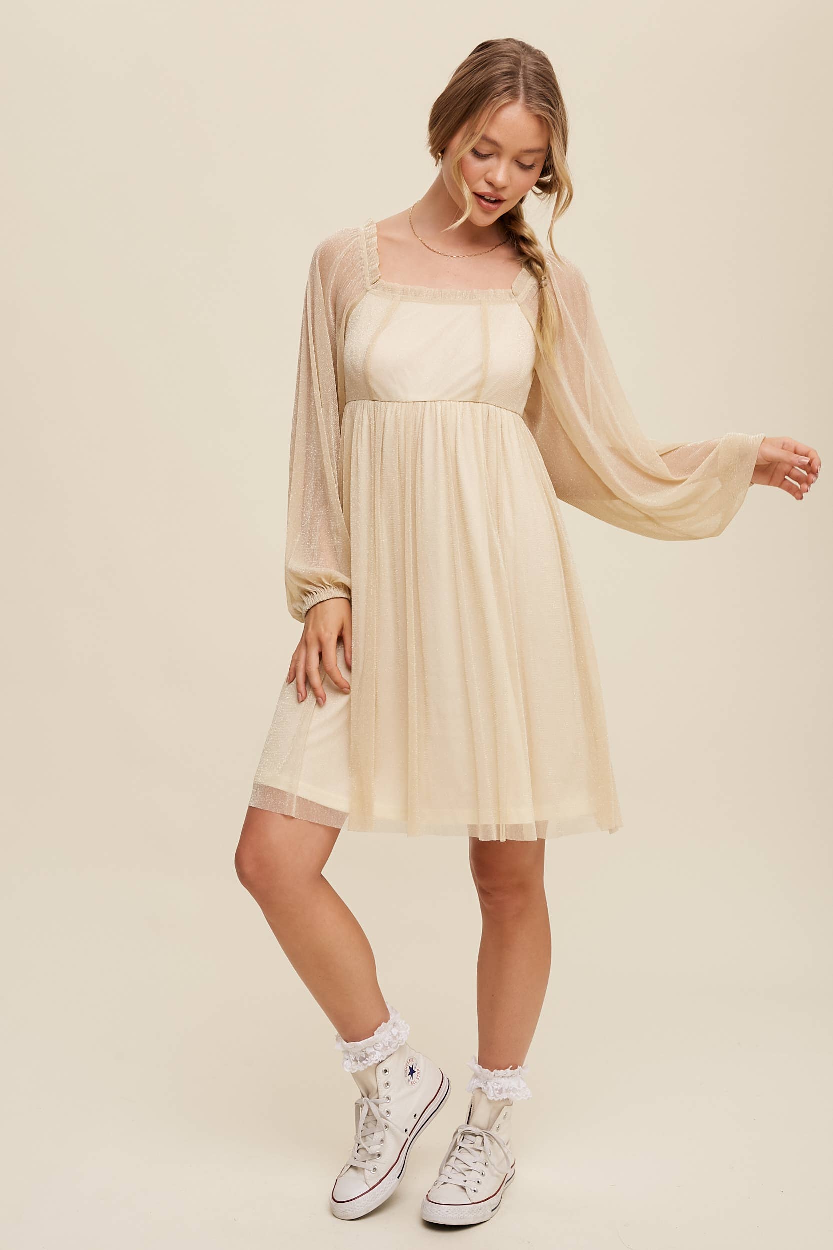 Full view Model wearing a beige shimmer mini dress with long sheer sleeves, square neckline, and flowy A-line silhouette — romantic sparkle party dress