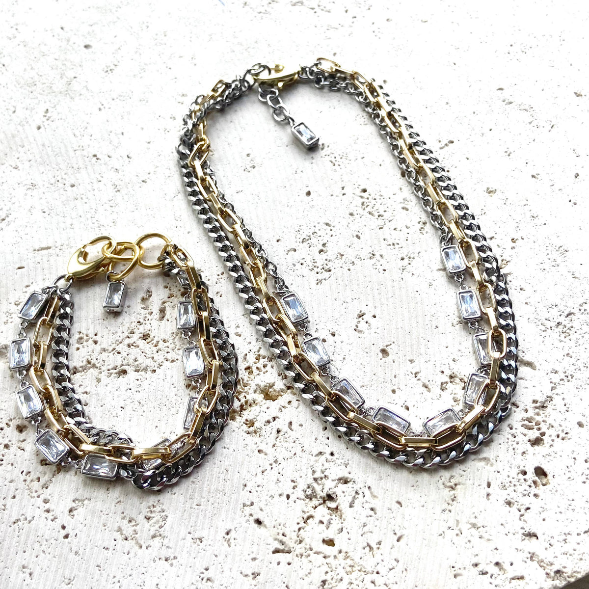 Necklace and bracelet set with chain design and embedded crystals on a textured surface