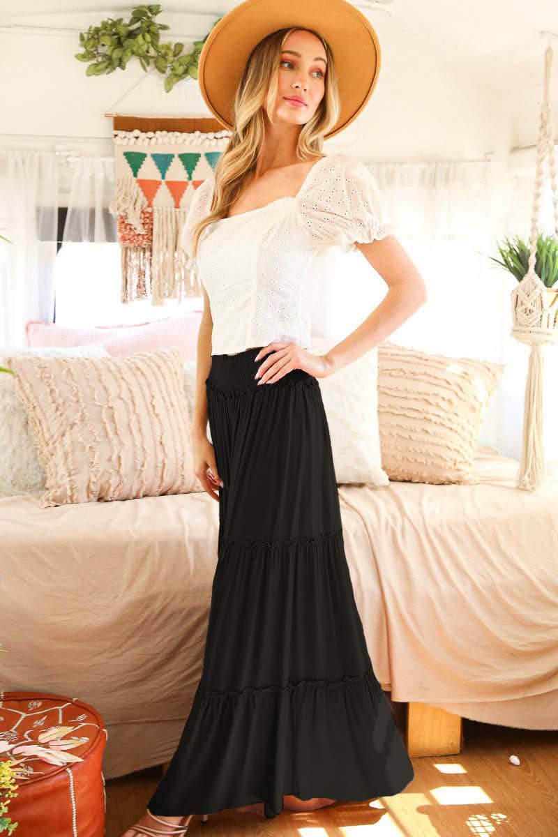 Woman wearing tiered palazzo pants with smocked waistband in mocha and black, styled for fall with sweater and boots.