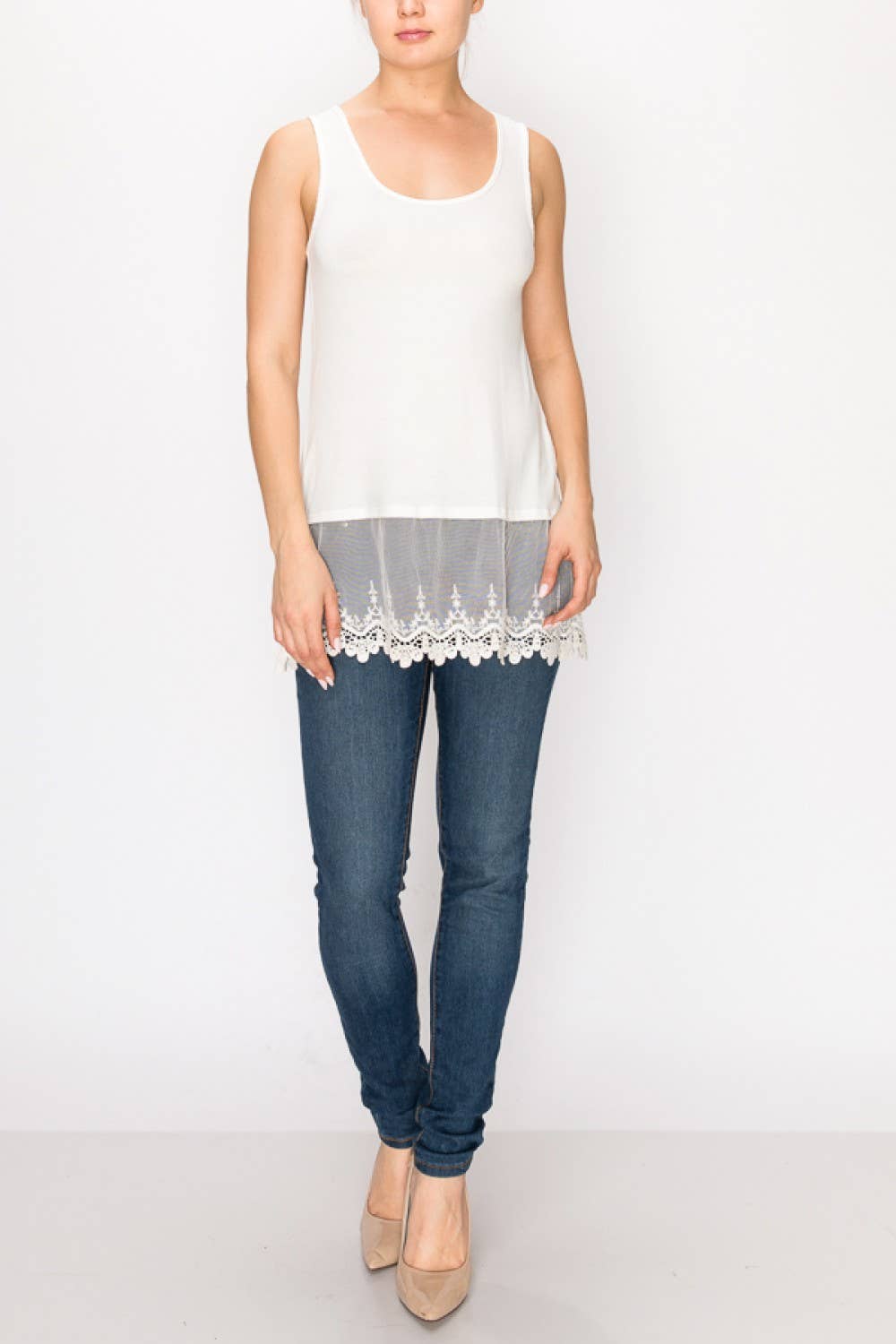 Woman wearing a white lace-trimmed top and blue jeans on a white background