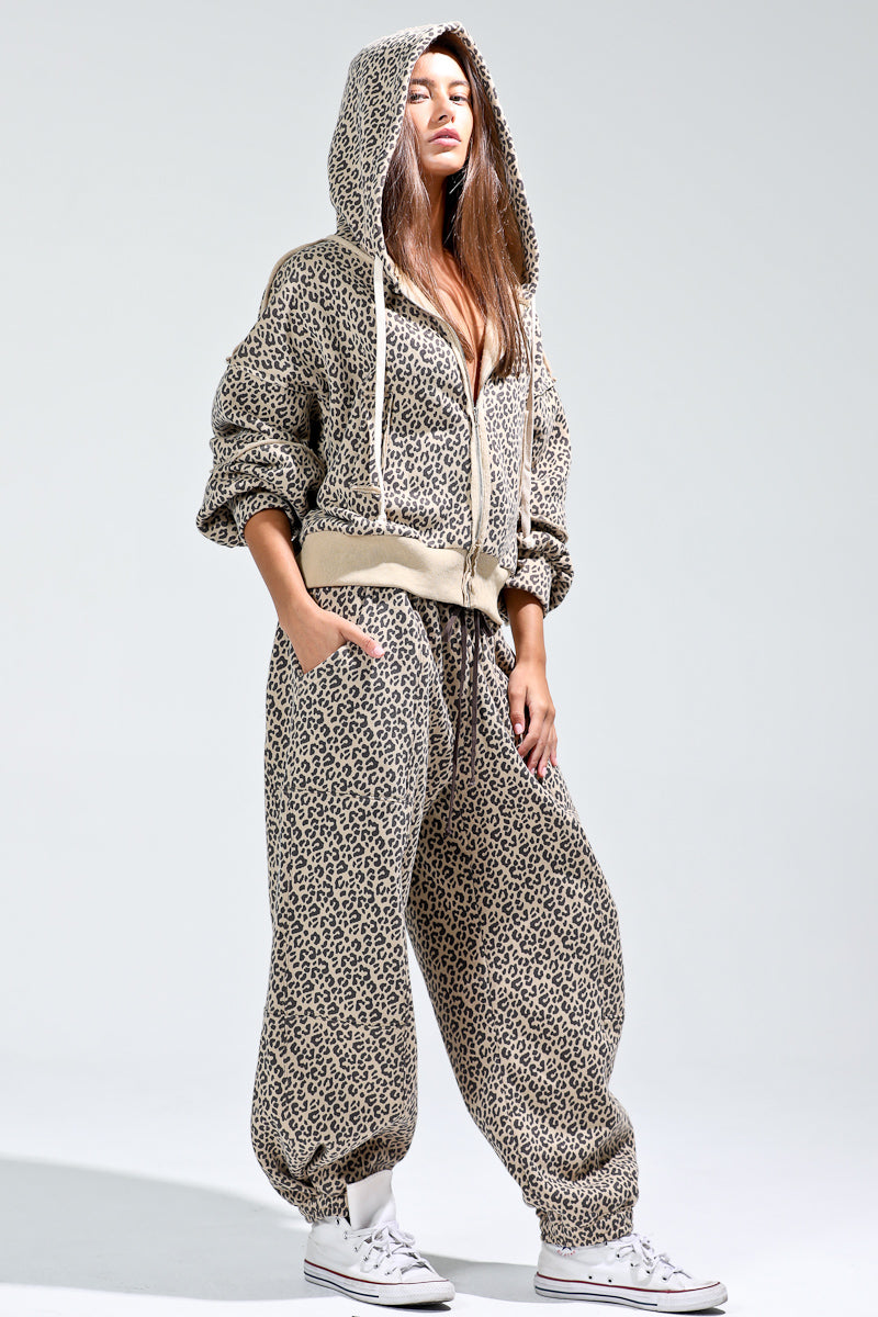 Person wearing a patterned hoodie and pants with white sneakers on a light gray background