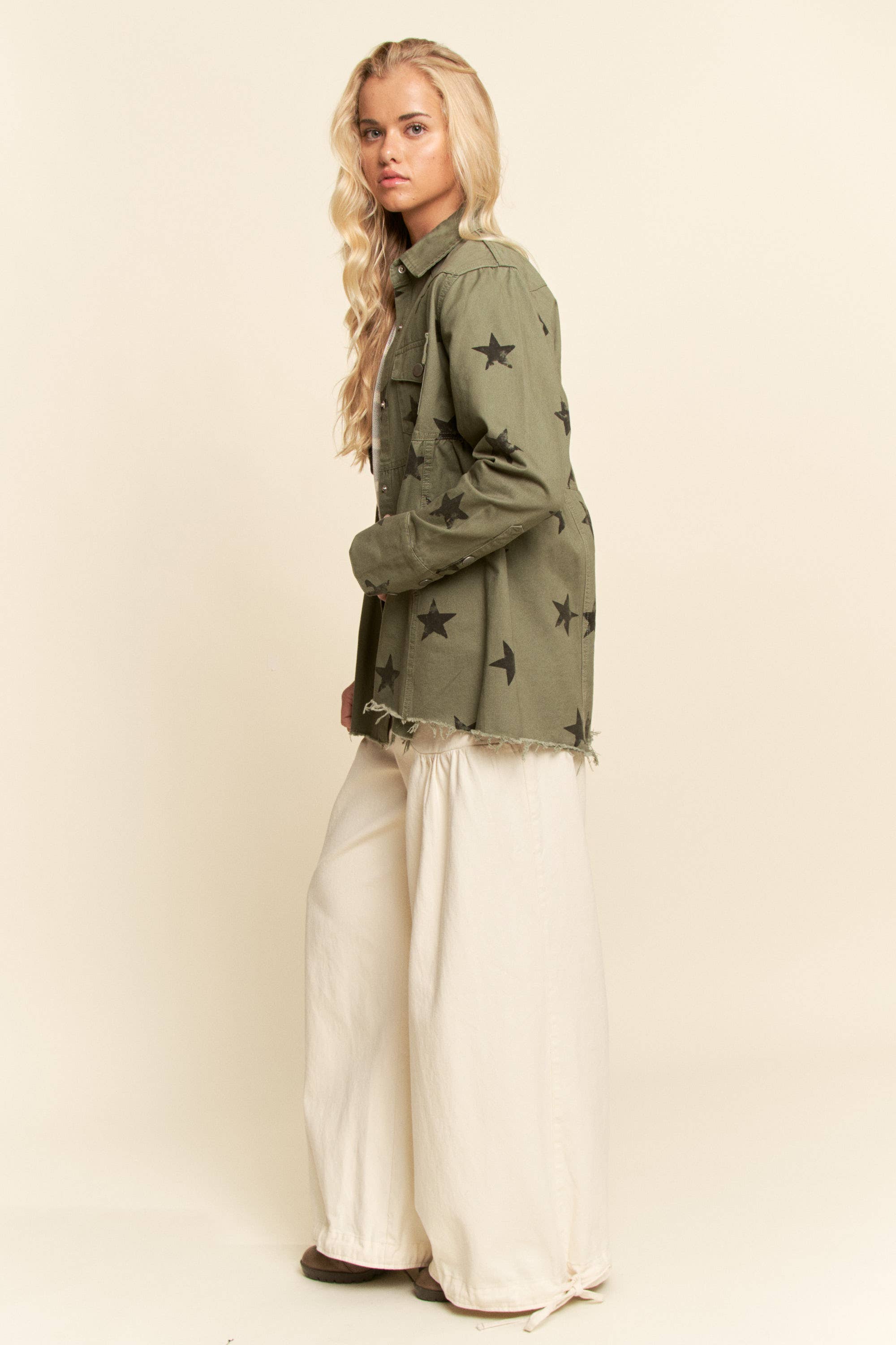 Side view- Olive star-print babydoll shacket with snap-button front, chest flap pockets, dropped shoulders, relaxed fit, and frayed curved hem.
