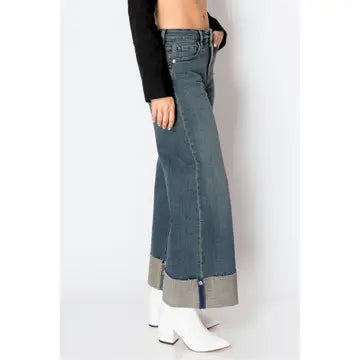 Side view — dark-wash high-rise wide-leg jeans with oversized cuffed hems and side zip vent, ankle length on model.