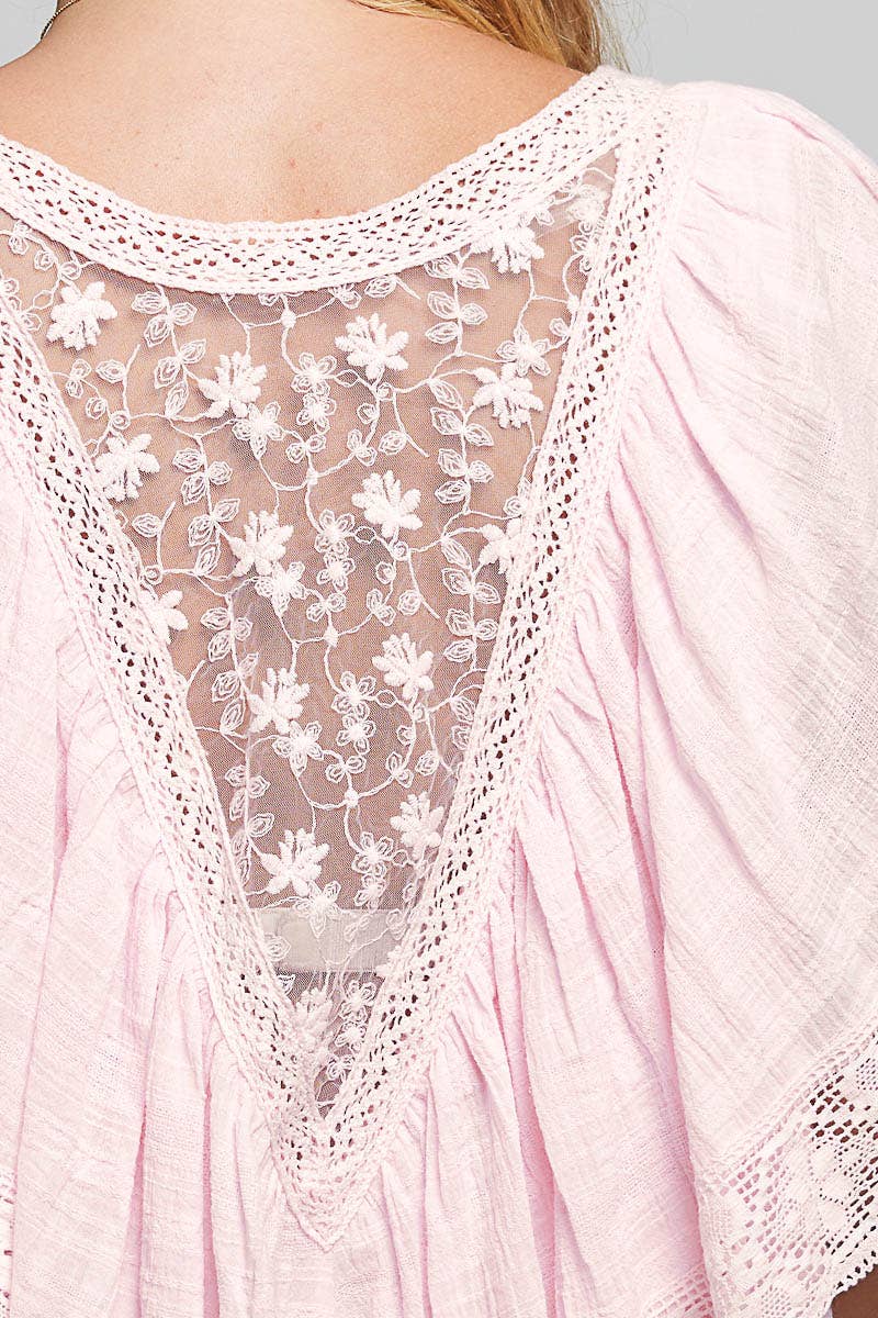 Close-up of pink reversible embroidered ruffle top showing sheer floral embroidery panel, V-ruffle layers, and lace trim detail