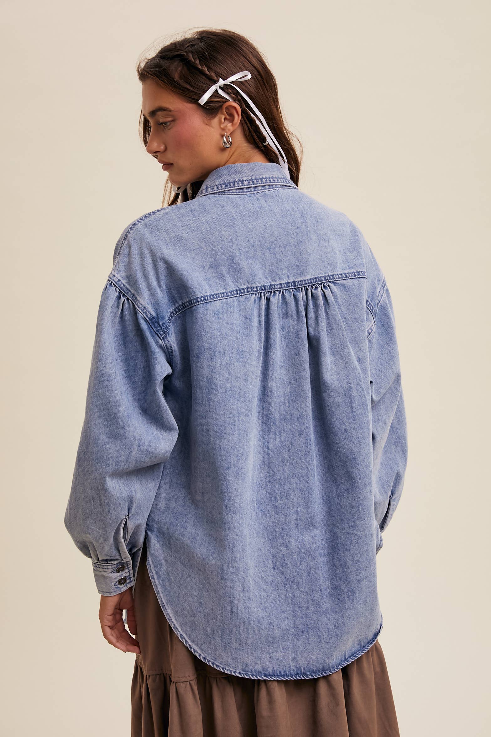 Back view- Light-wash oversized denim shacket with a heart-shaped chest pocket, button front, drop shoulders, balloon sleeves, and a curved hem.