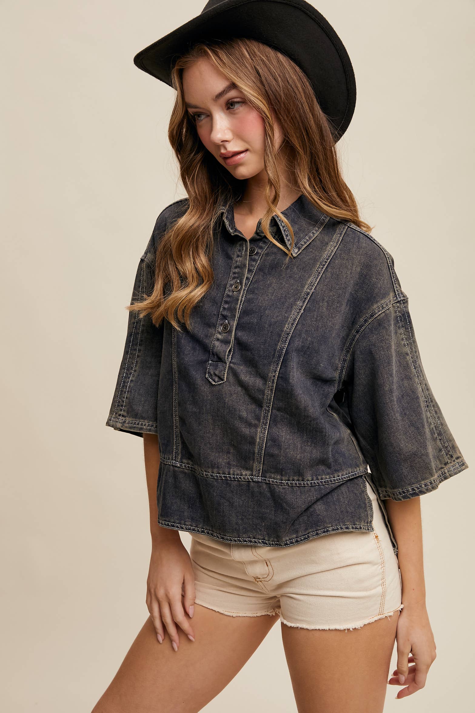 Dark-wash denim pullover top with half-button placket, exposed seam panels, and wide elbow-length sleeves in a relaxed, boxy fit.