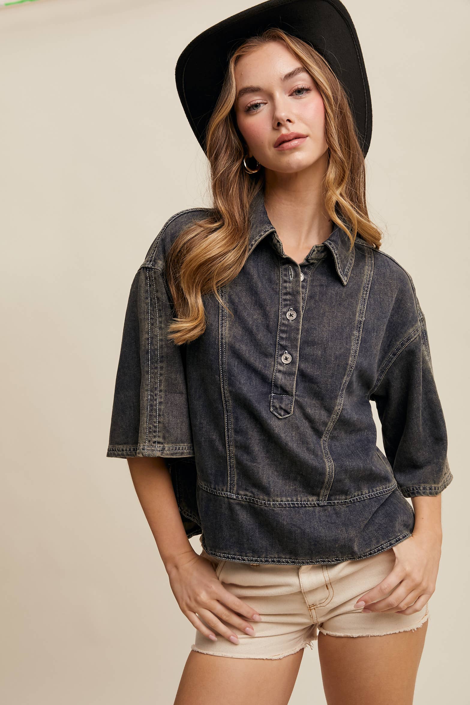 Dark-wash denim pullover top with half-button placket, exposed seam panels, and wide elbow-length sleeves in a relaxed, boxy fit.