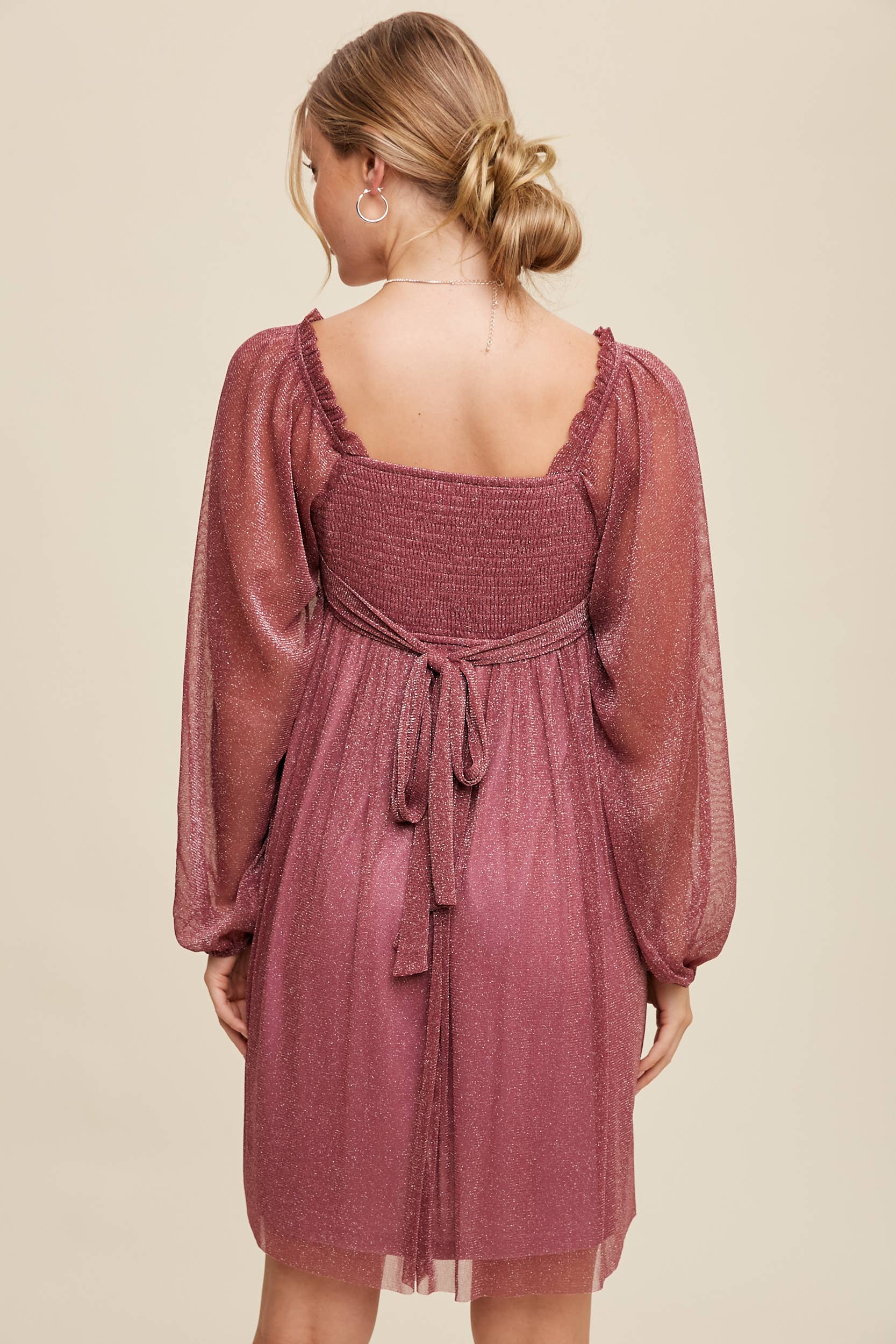 Back view Model wearing a mauve shimmer mini dress with long sheer sleeves, square neckline, and flowy A-line silhouette — romantic sparkle party dress