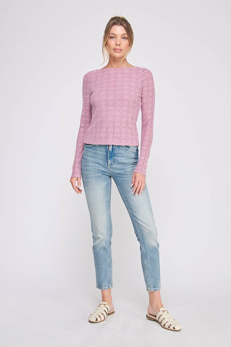 Woman wearing a pink textured top and light blue jeans on a white background