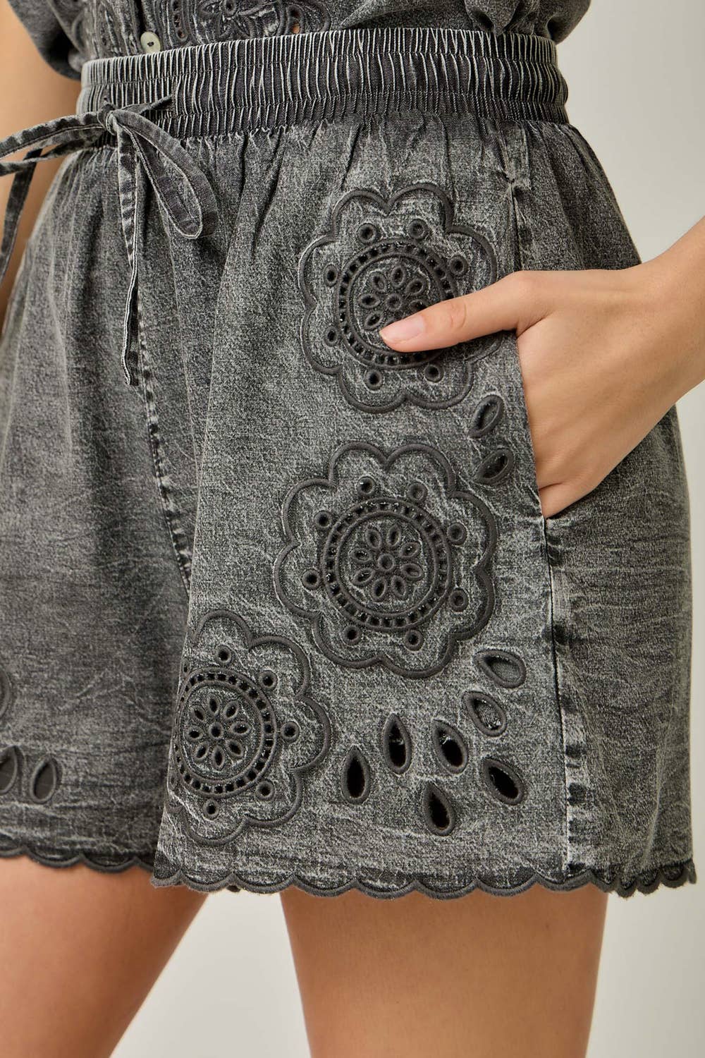 Close up view Eyelet Embroidered Washed Tencel Shorts in Acid Black — thigh length with eyelet embroidery, scallop hem, and side pockets