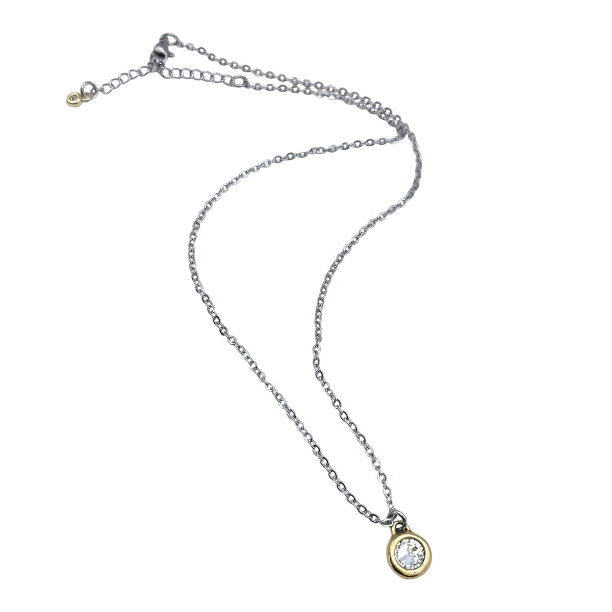 A delicate silver chain necklace with an oval pendant featuring a clear gemstone in a gold bezel setting, displayed on a plain white background.
