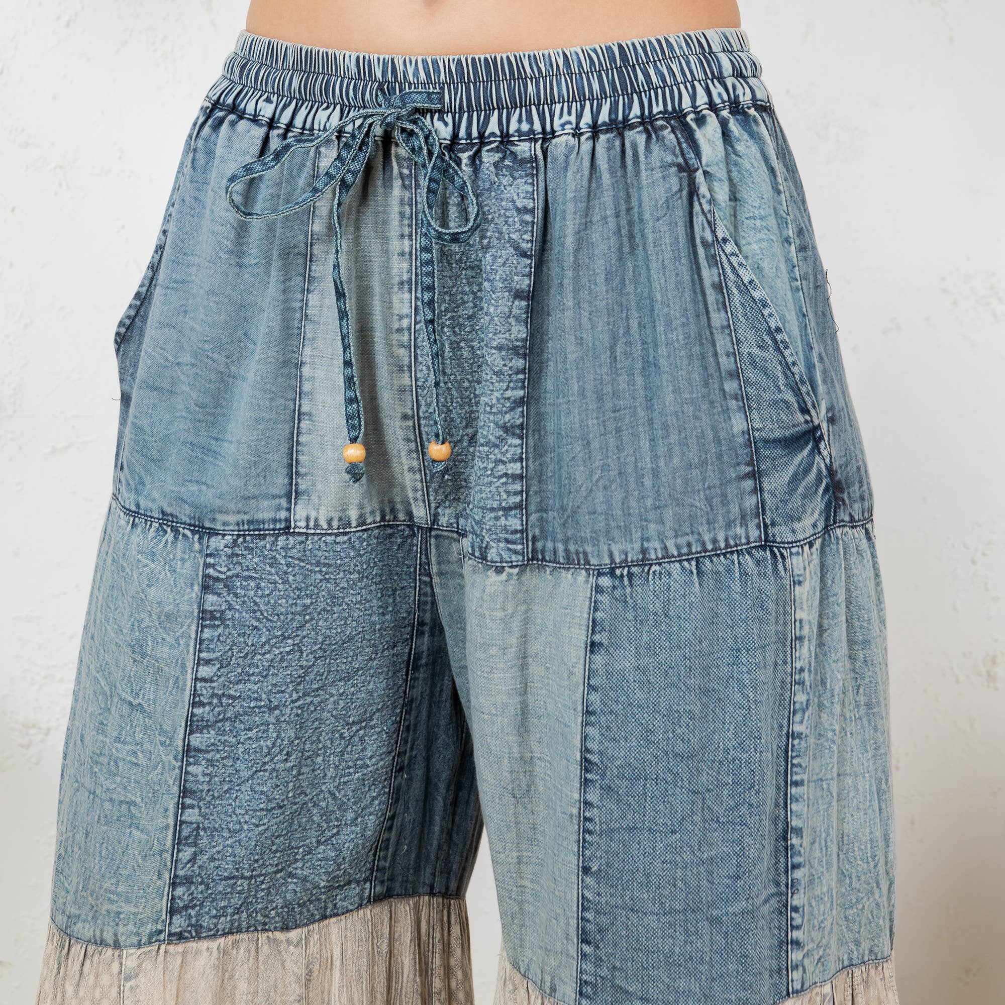 Boho patchwork pants detail - close-up of intricate embroidery, denim patches and jacquard lace inserts