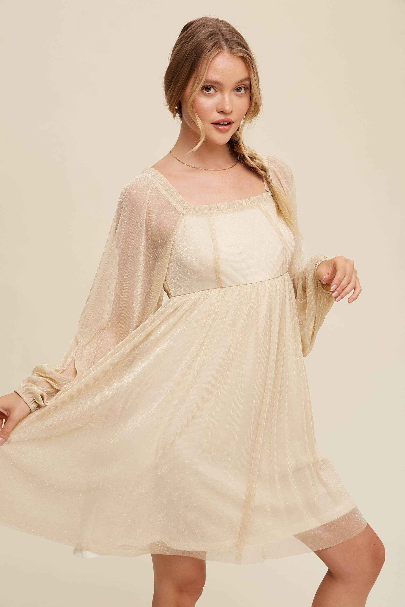 Model wearing a beige shimmer mini dress with long sheer sleeves, square neckline, and flowy A-line silhouette — romantic sparkle party dress