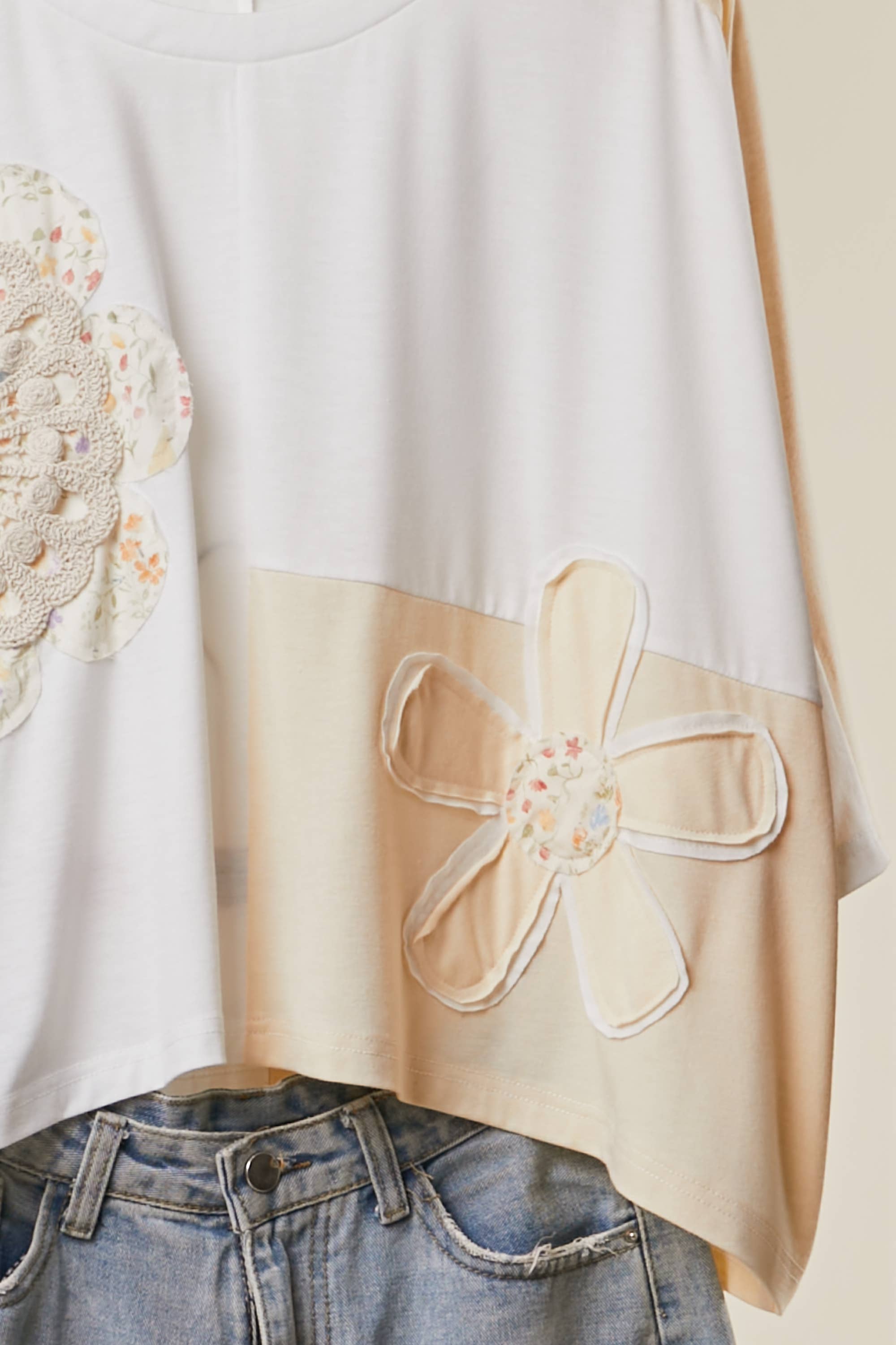 close up detail The Cleo Crochet Patchwork Top in Cream — oversized patchwork silhouette with crochet medallion patch and flower appliqué detail, boho-luxe ivory and cream colorblock top