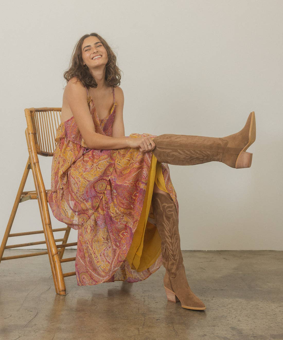 Taupe suede knee-high western boot with stitched shaft, pull tab, pointed toe, and stacked block heel, side view.
