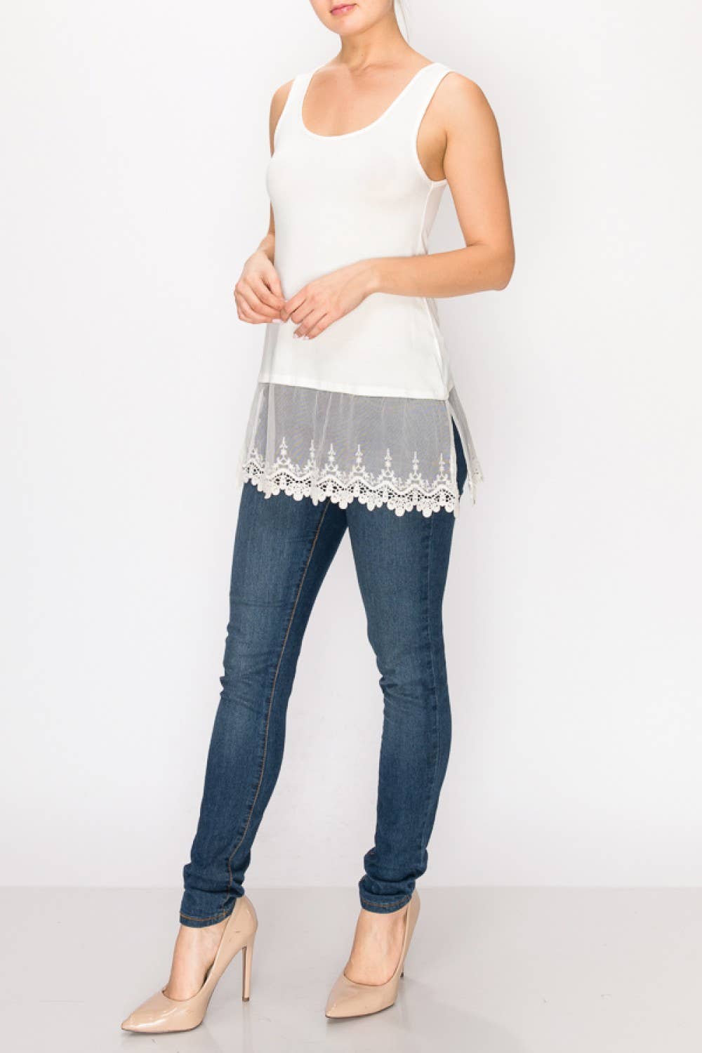 Woman wearing a white lace top and blue jeans on a white background
