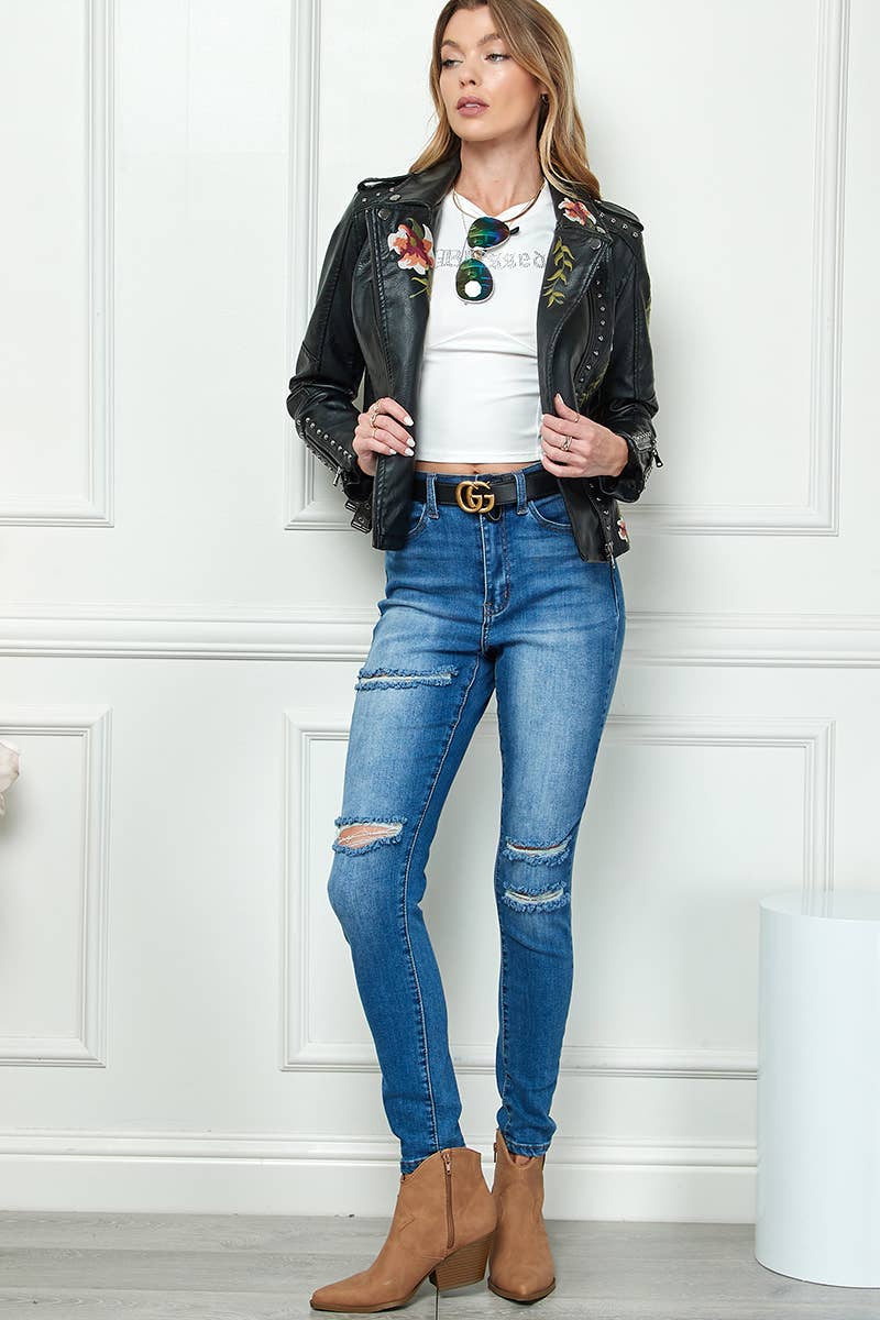 Black faux-leather moto jacket with floral embroidery and silver studs, styled with a white crop top and high-waisted blue jeans.