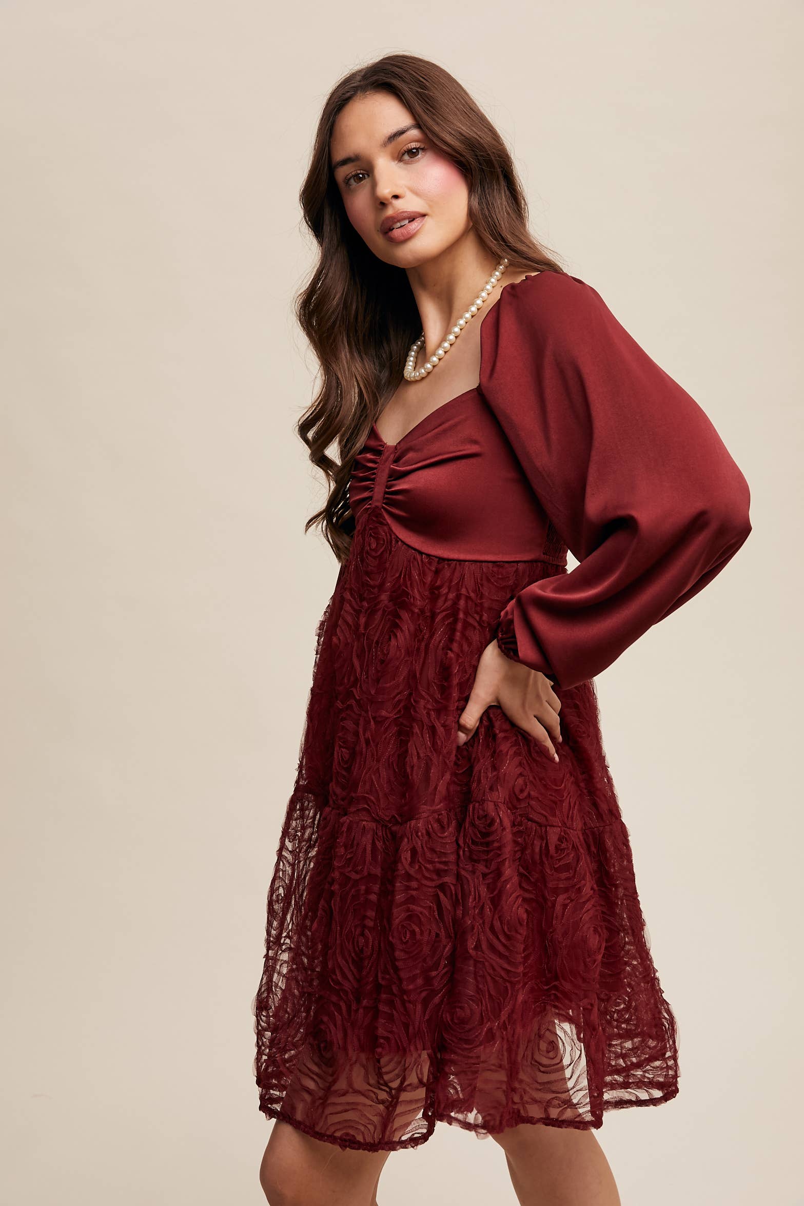 Side view of Model wearing oxblood red rosette mini dress with ruched sweetheart neckline, puff long sleeves, and tiered lace skirt — elegant and romantic look.