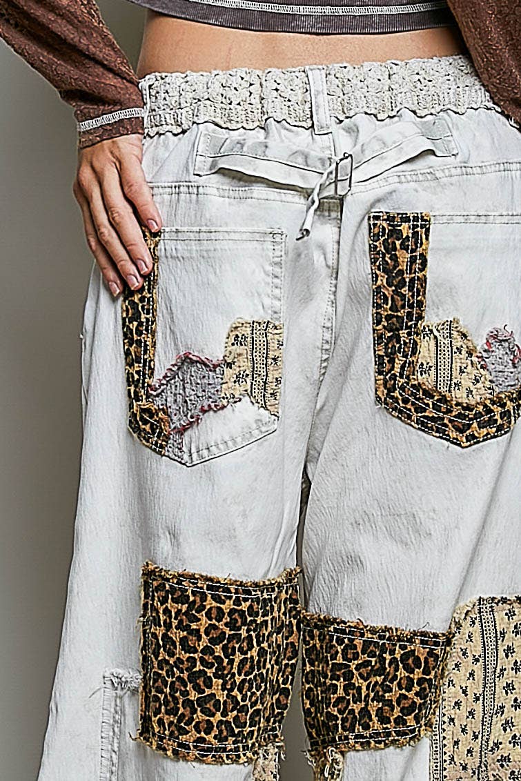 Light-colored pants with leopard print accents and embellishments on a neutral background
