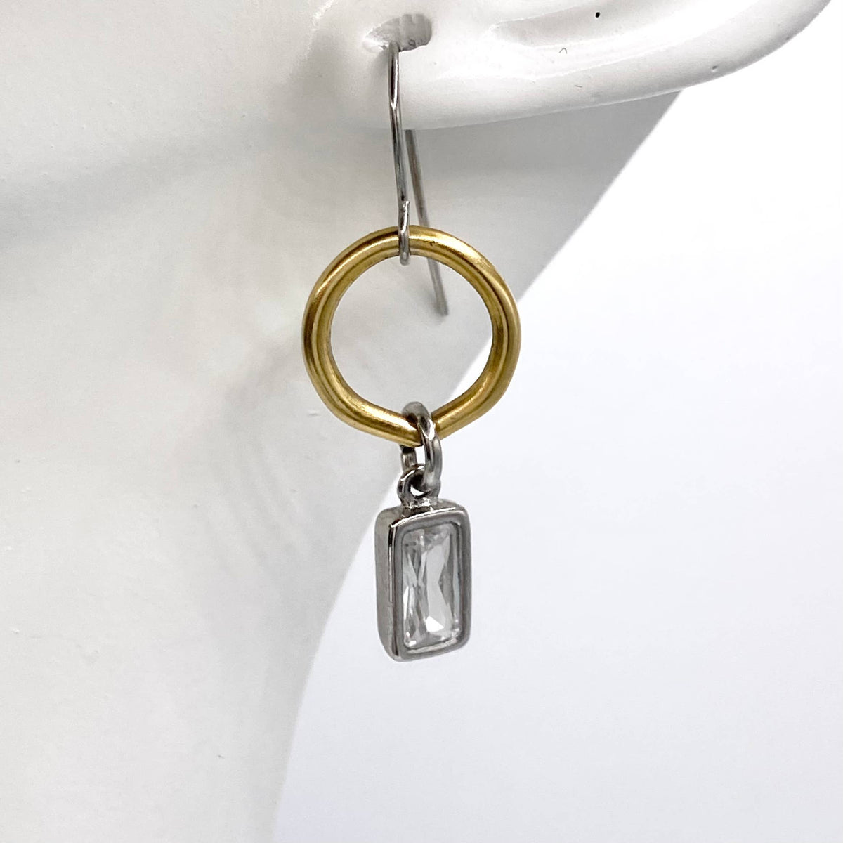 Gold and silver earring on a white stand