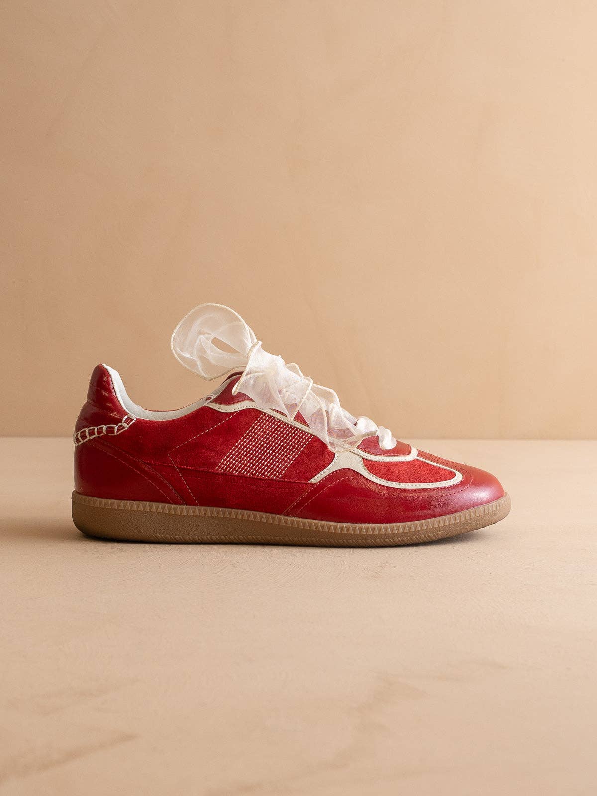 Cherry red Oasis Society sneakers with cream detailing and two lace options — organza ribbon and classic cotton.