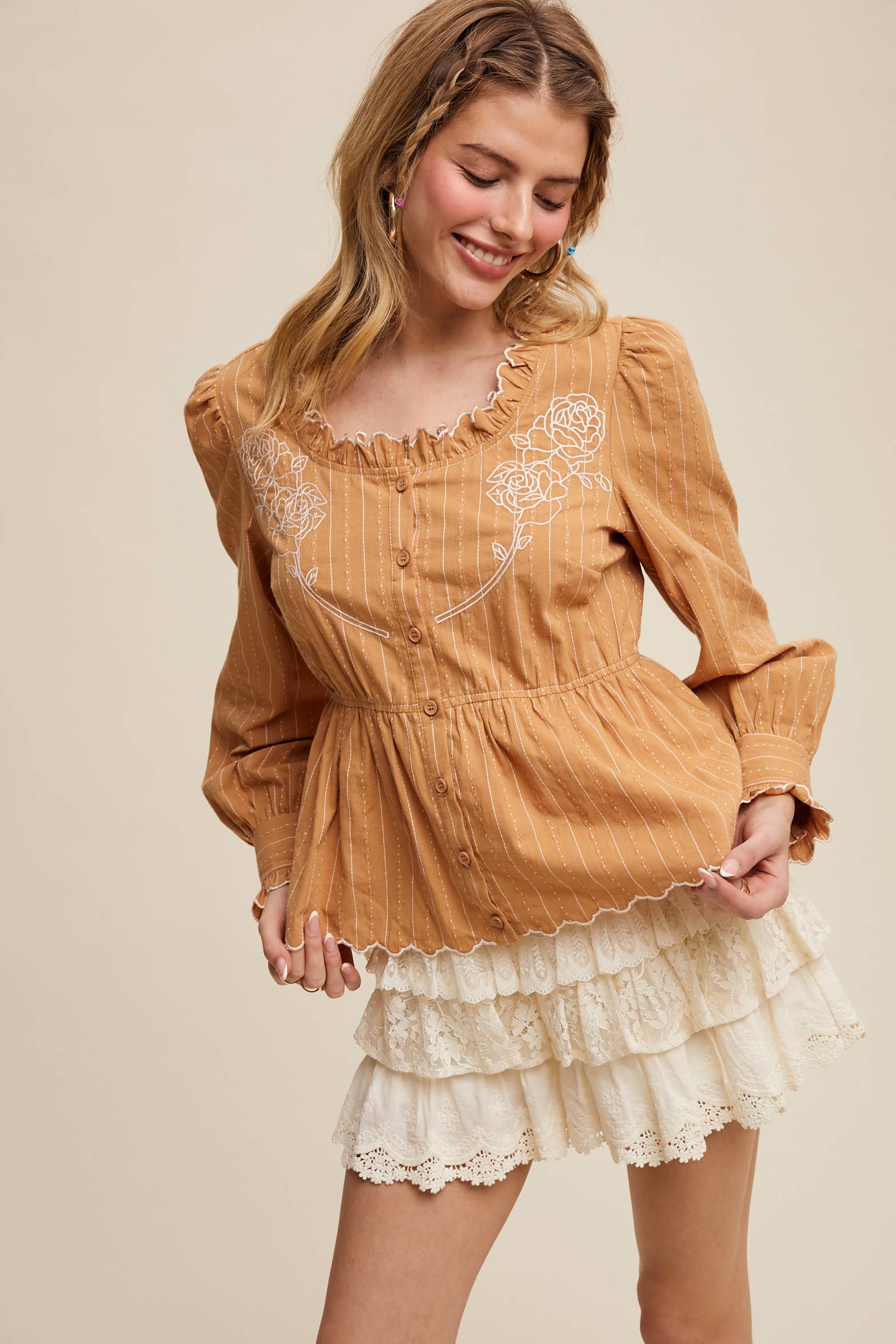 Camel pinstripe blouse with ruffled neckline, white rose embroidery, puff long sleeves, button front, and scalloped peplum hem—styled with white lace shorts.