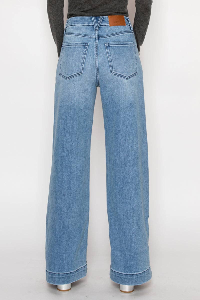 Rear view of model wearing ultra high-rise wide-leg jeans in medium stone wash with cuff detail and button accents along the leg