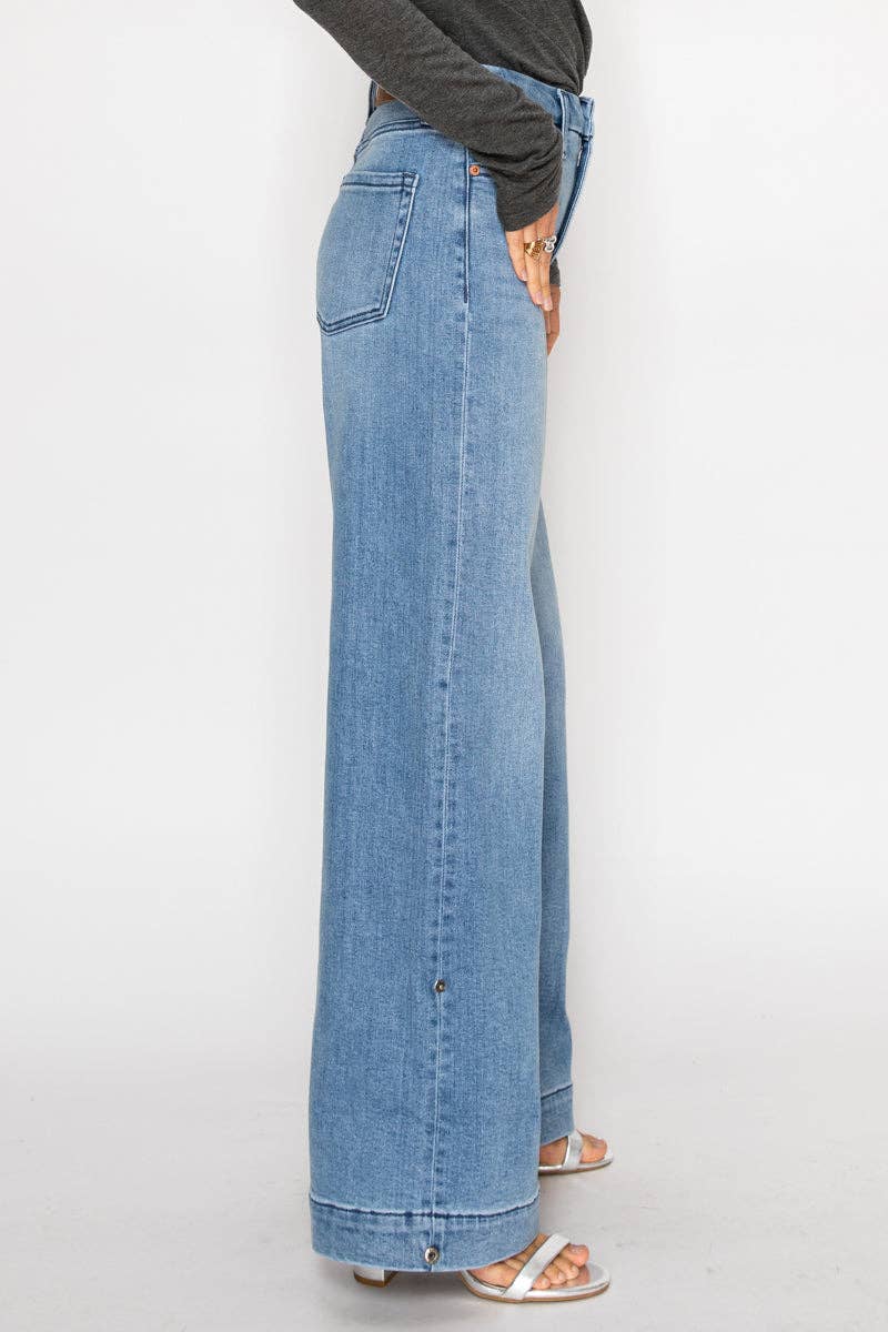 Side view of model wearing ultra high-rise wide-leg jeans in medium stone wash with cuff detail and button accents along the leg