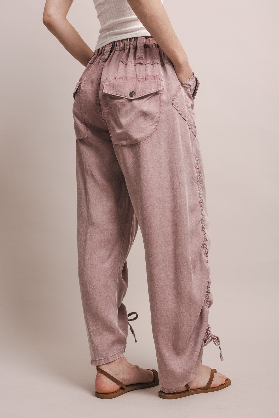 Person wearing pink pants with drawstring details on a plain background