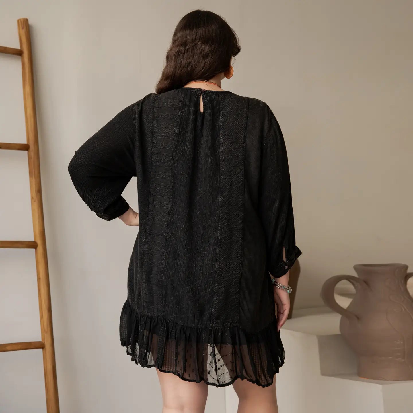 Back view of plus size black embroidered babydoll dress showing keyhole neckline, patchwork sleeves, and sheer ruffle hem