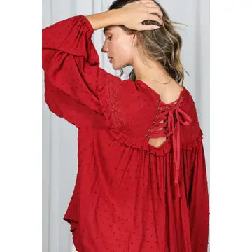 Back view of burgundy Swiss dot blouse showing lace-up eyelet closure and flowy fit-and-flare silhouette — Spirit & Wind Boutique