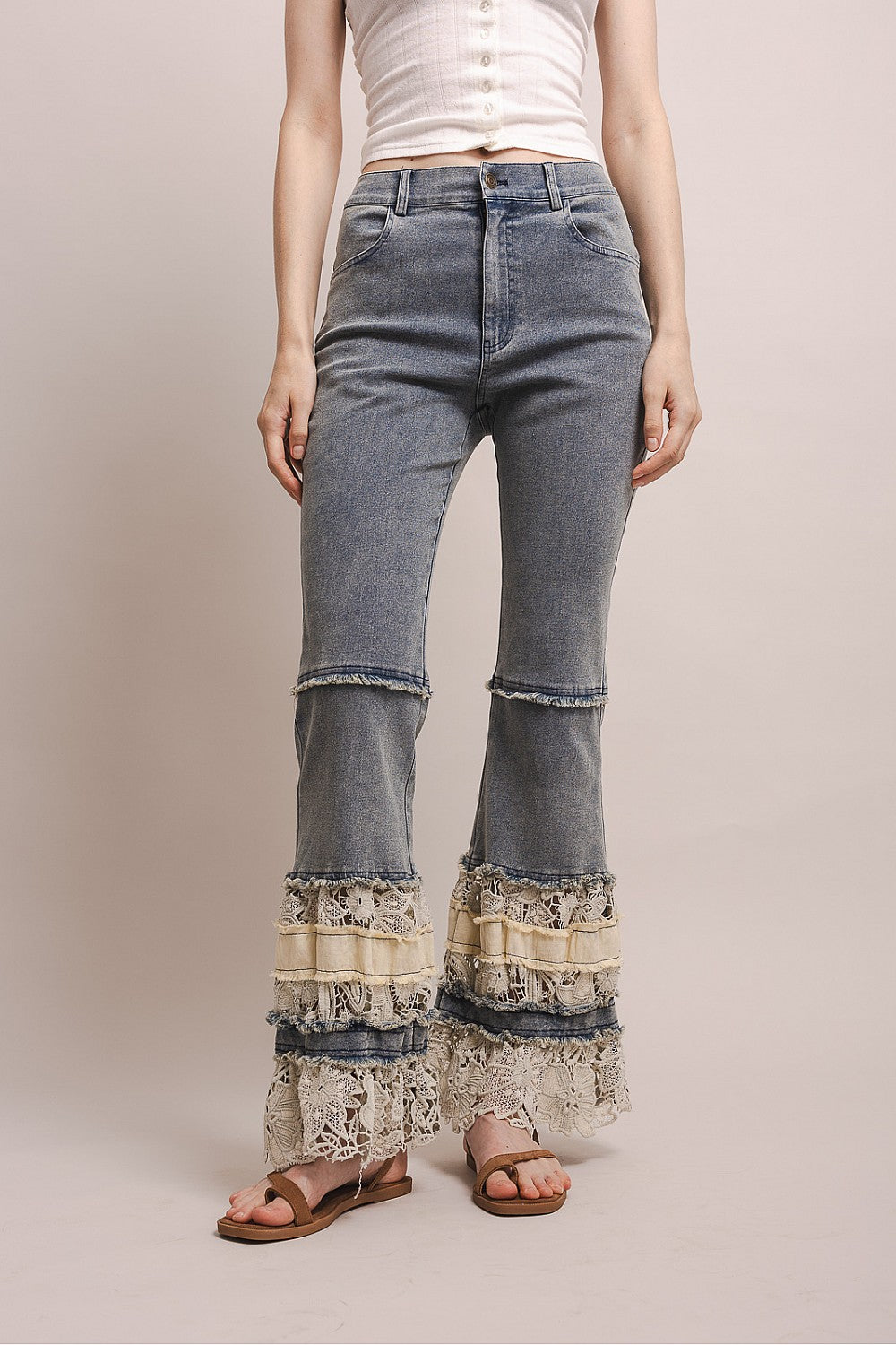 Flared jeans with lace detailing on a plain background