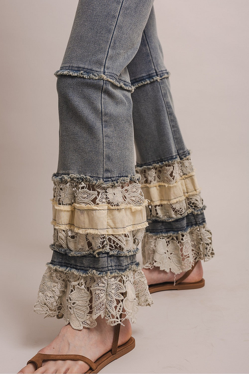 Denim pants with lace ruffles on a neutral background