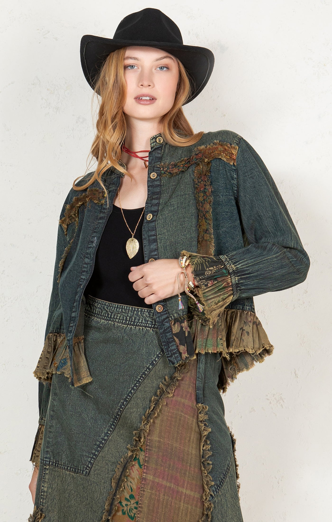 Woman wearing a patchwork denim jacket and hat against a white background