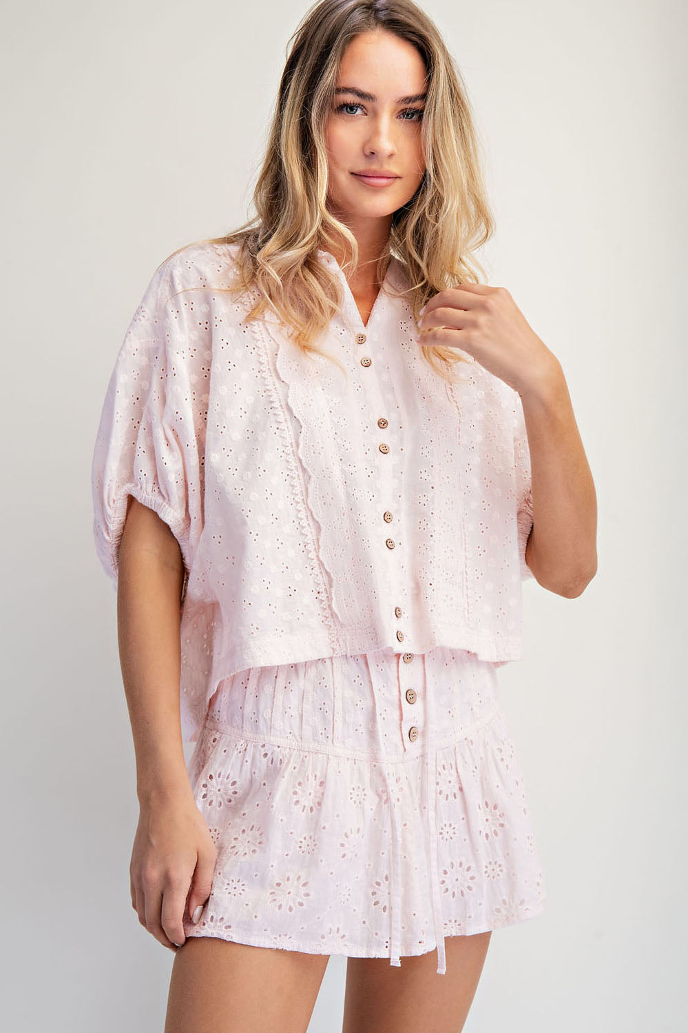 Woman wearing a light pink lace outfit on a plain background