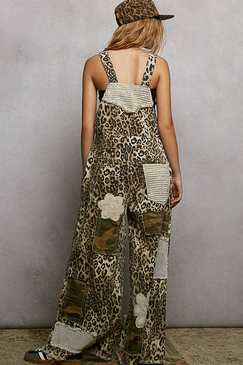 Back view of model wearing Boho leopard print patchwork overalls featuring wide legs, crochet lace appliqué details, and distressed accents. Styled with a leopard hat and black crop top for a trendy, eclectic look.