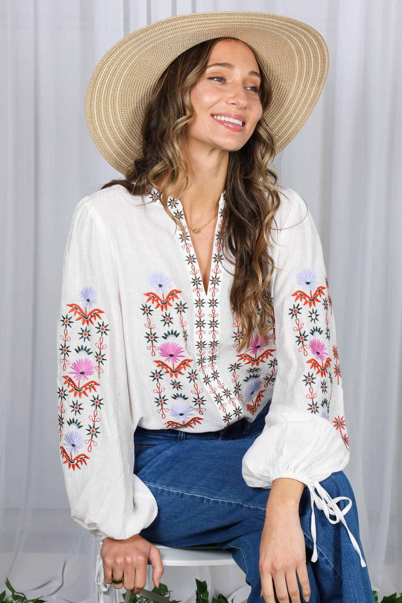 White embroidered peasant blouse with multicolor floral front, split V-neck, and balloon sleeves with ties