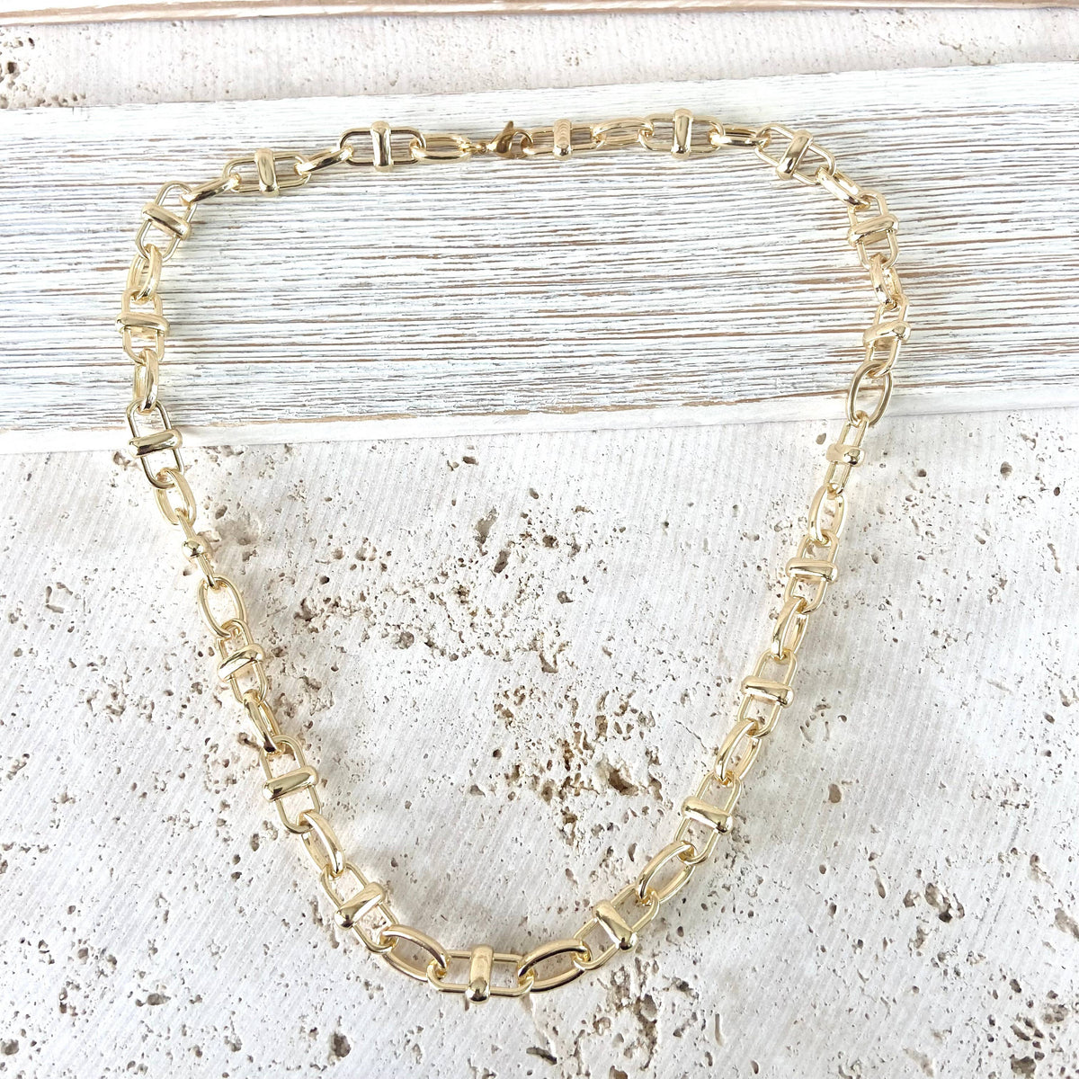 Gold chain necklace on a textured white surface