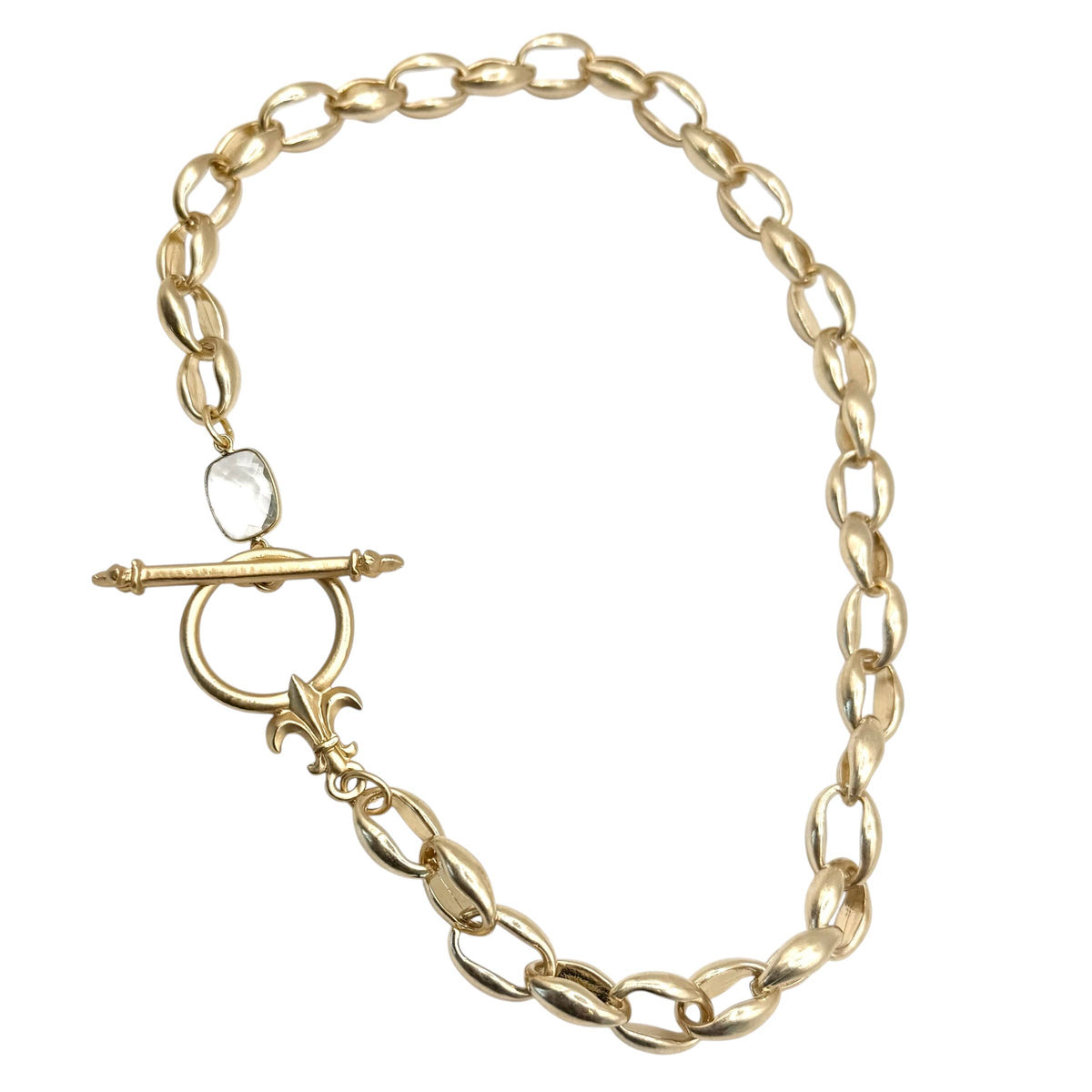 A gold chain link bracelet with a toggle clasp featuring a small clear teardrop gemstone, displayed on a solid white background.