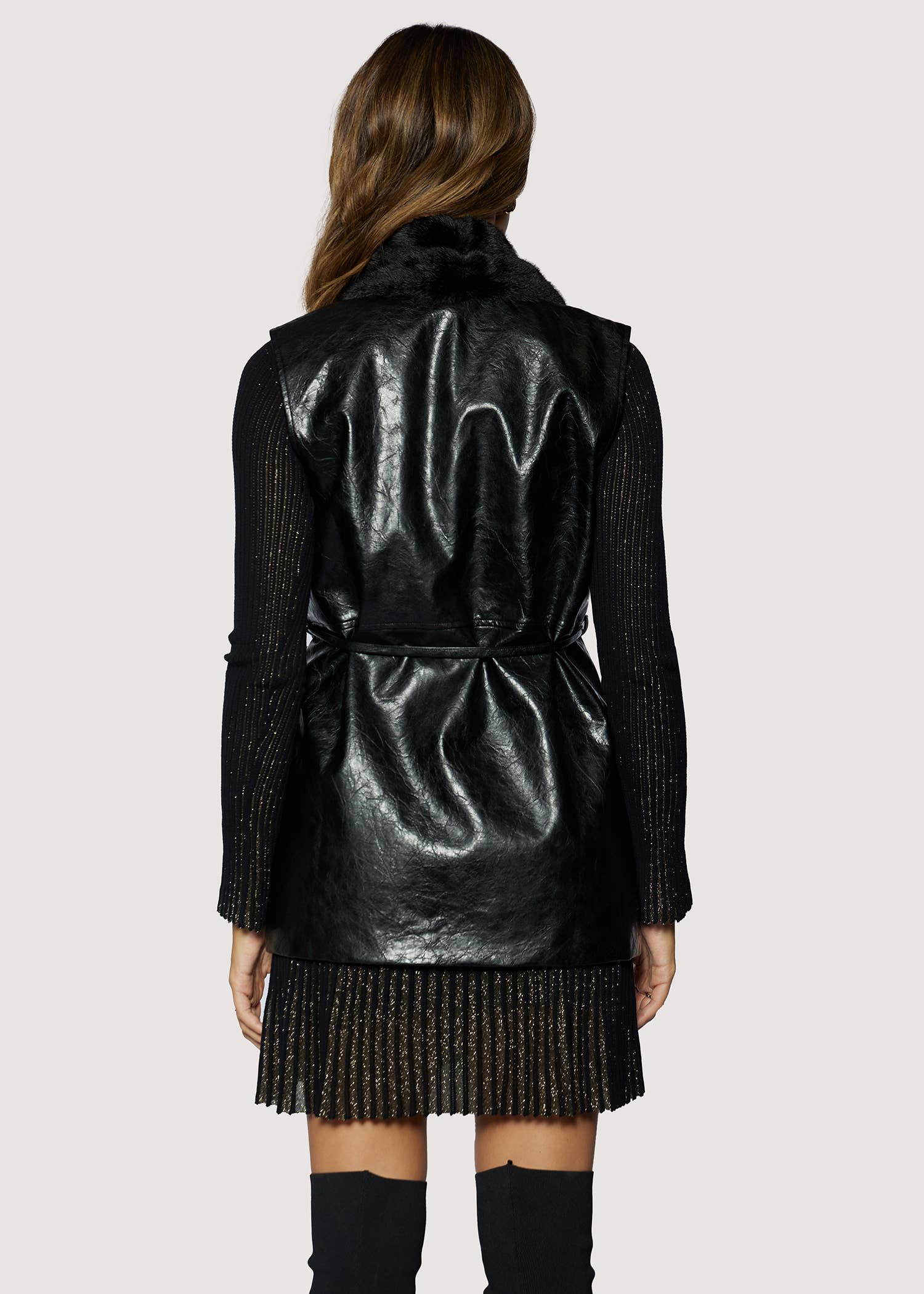 Person wearing a black metallic jacket and skirt on a white background