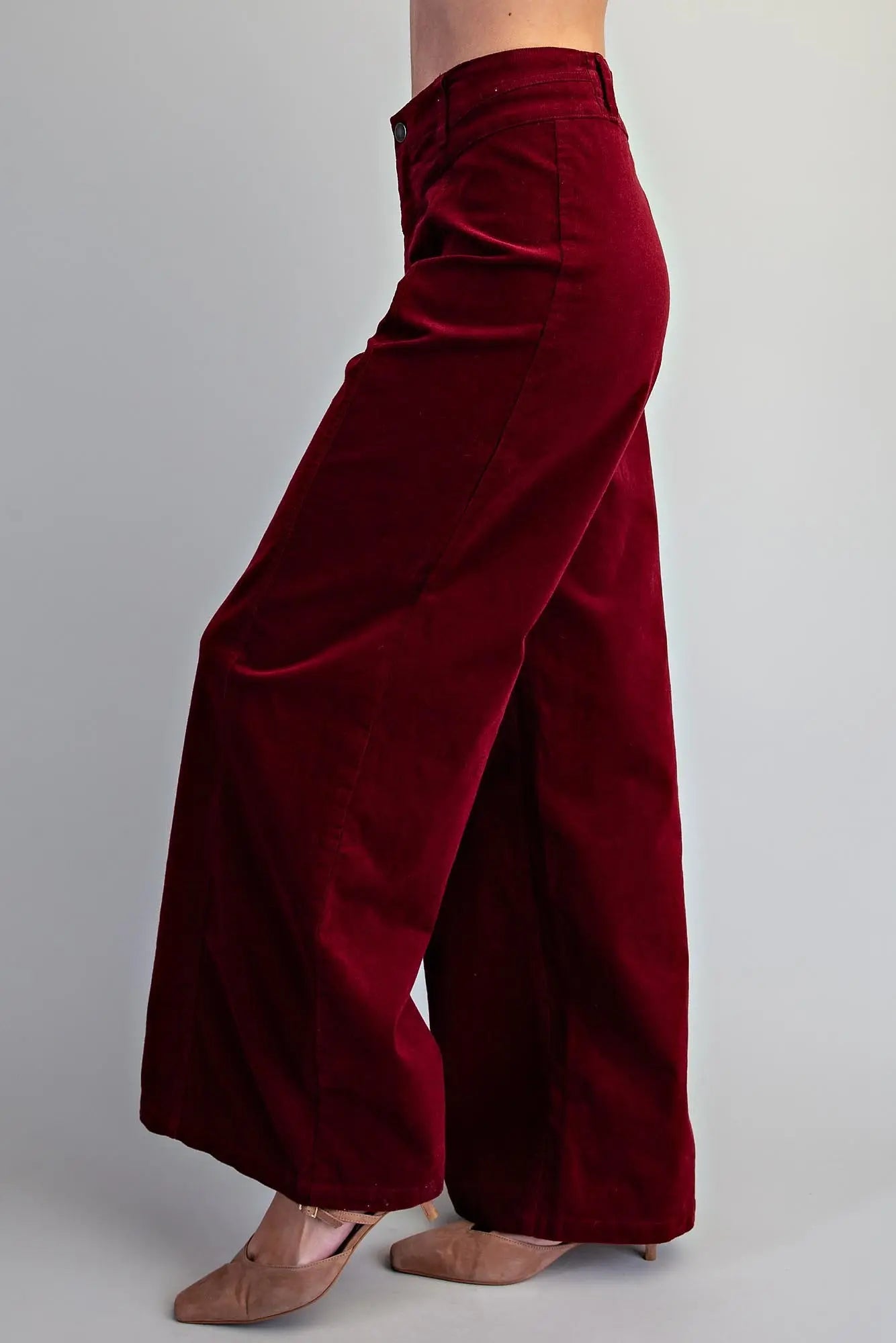 Side view of women's high-rise crimson corduroy wide-leg pants showing dramatic flare silhouette and clean waistband detail 