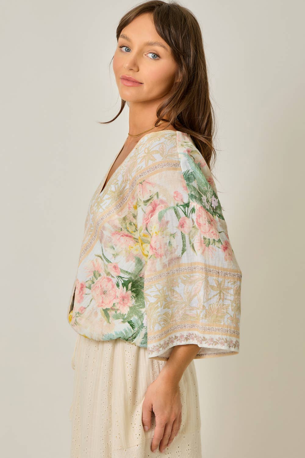 Woman wearing a floral kimono-style top against a plain background