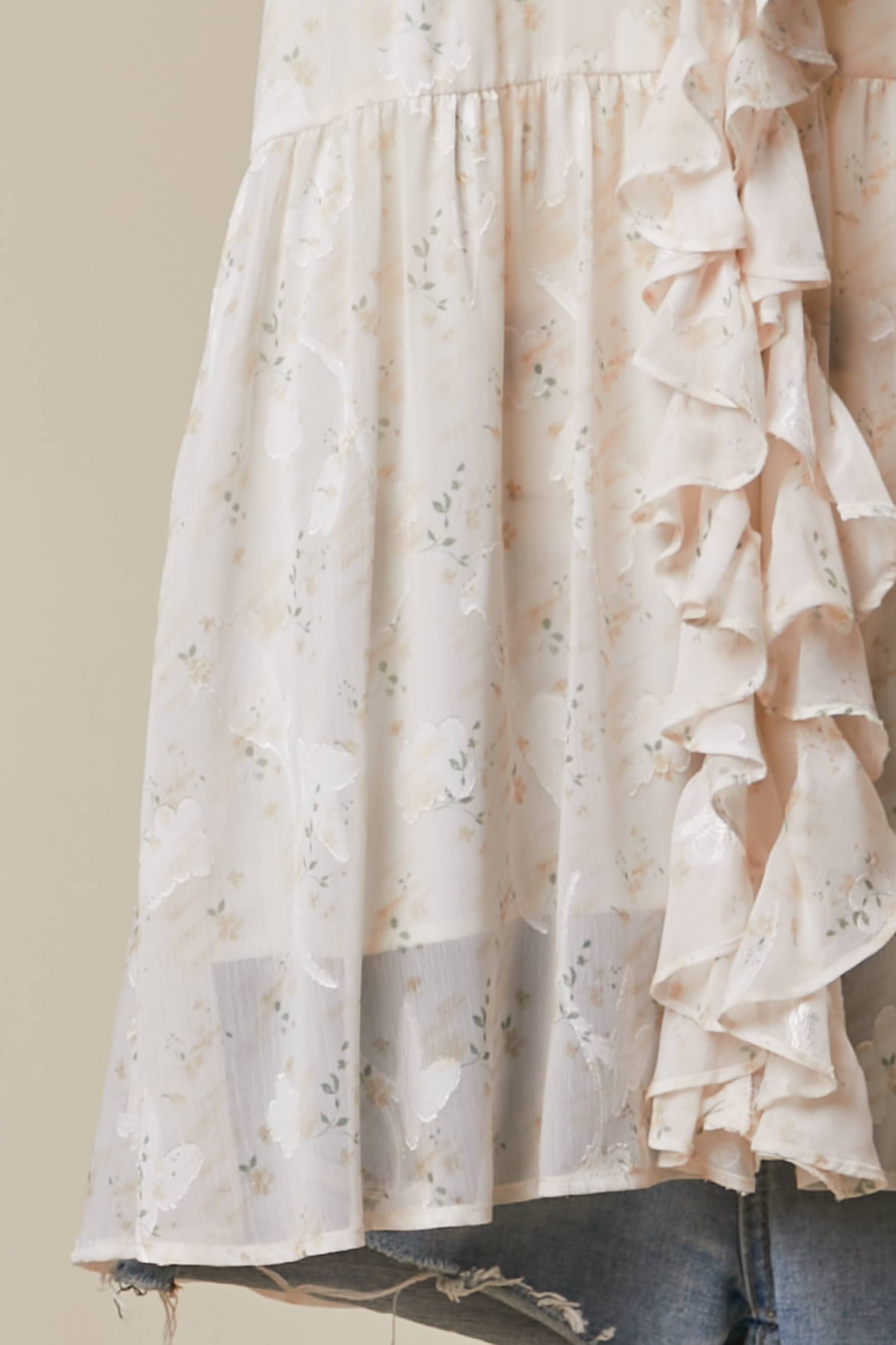 Elegant floral tunic detail - close-up of romantic ruffled accents and lightweight flowing fabric