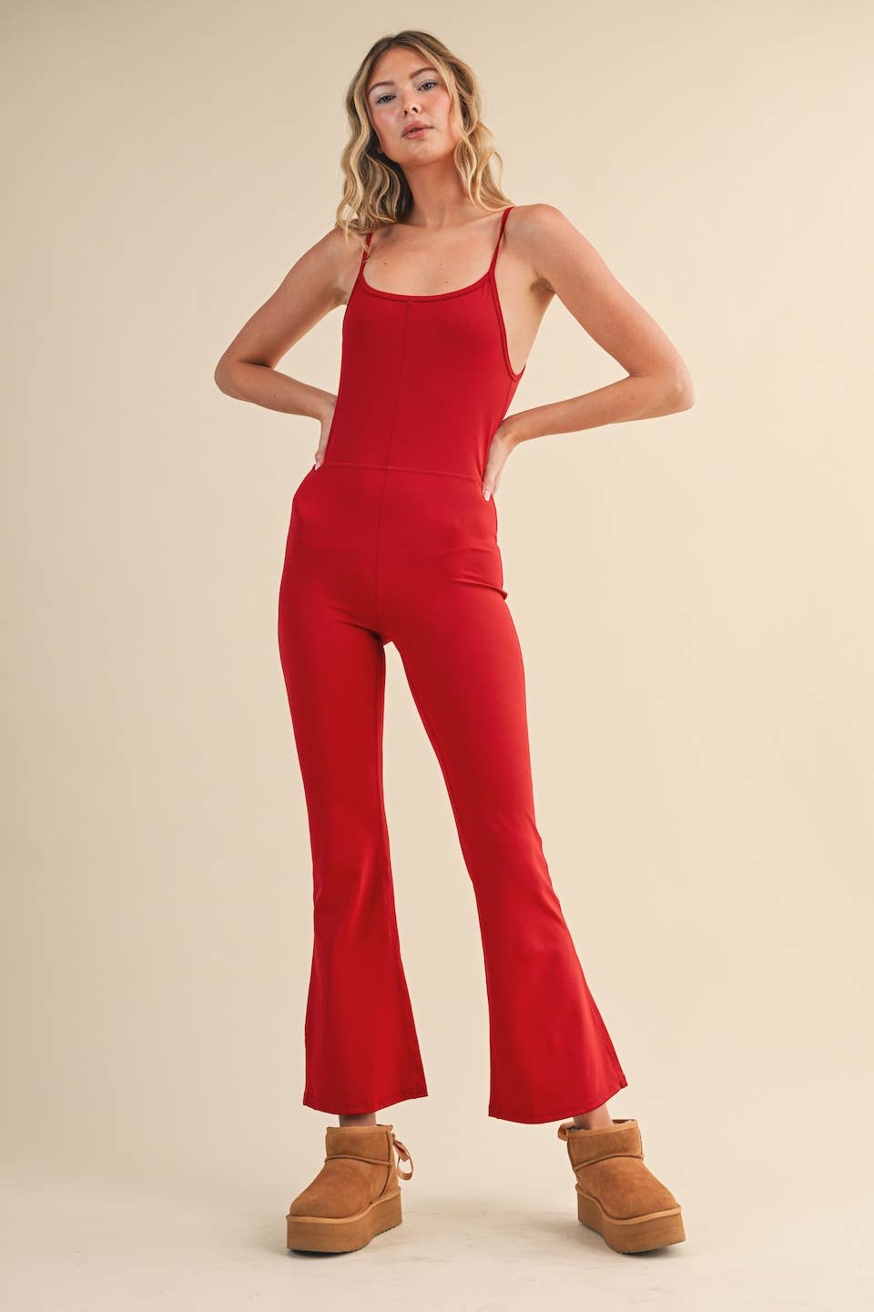 Woman wearing Kimberly C flare jumpsuit in cherry red with scoop neckline and flared leg.