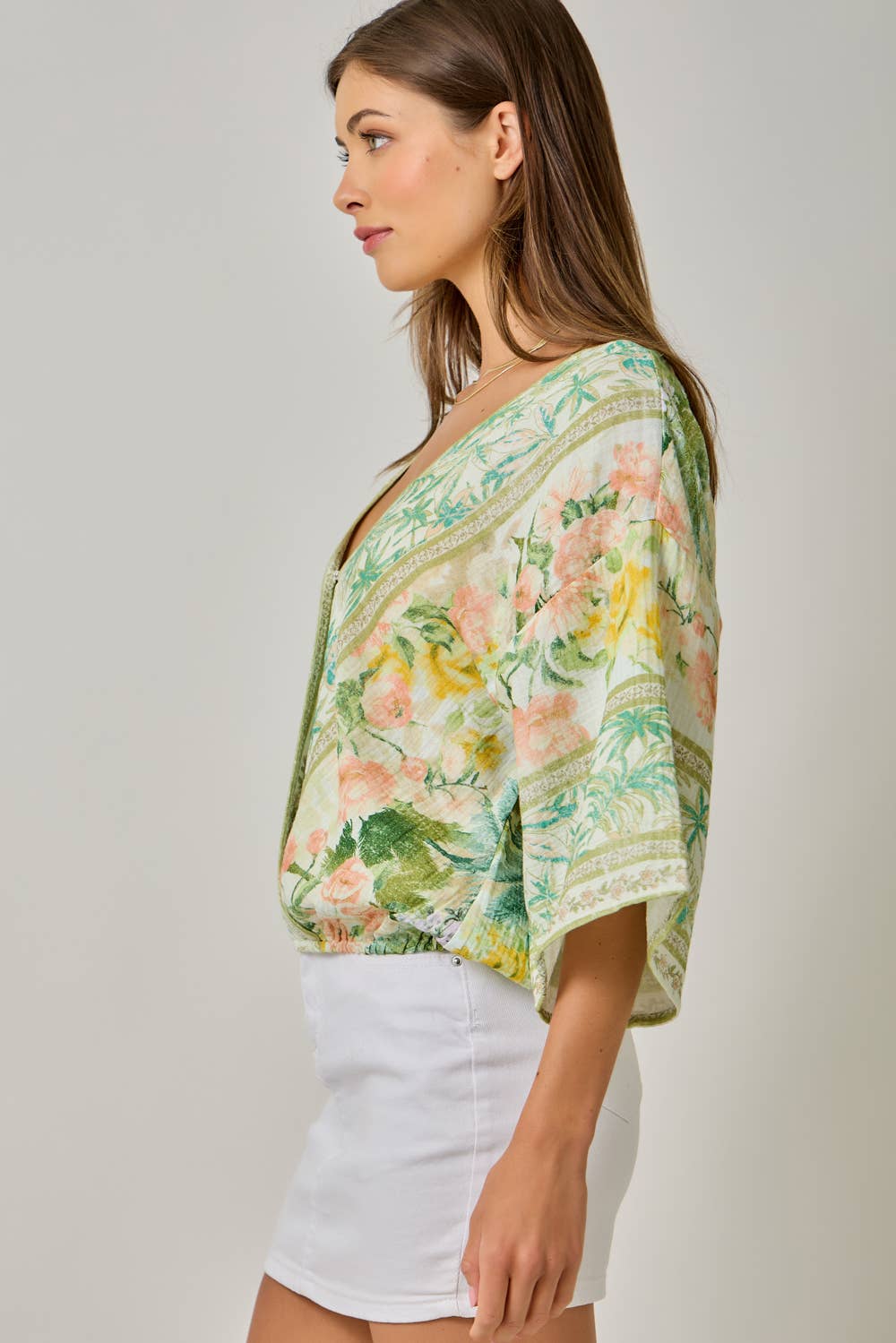 Woman wearing a floral kimono-style top against a plain background