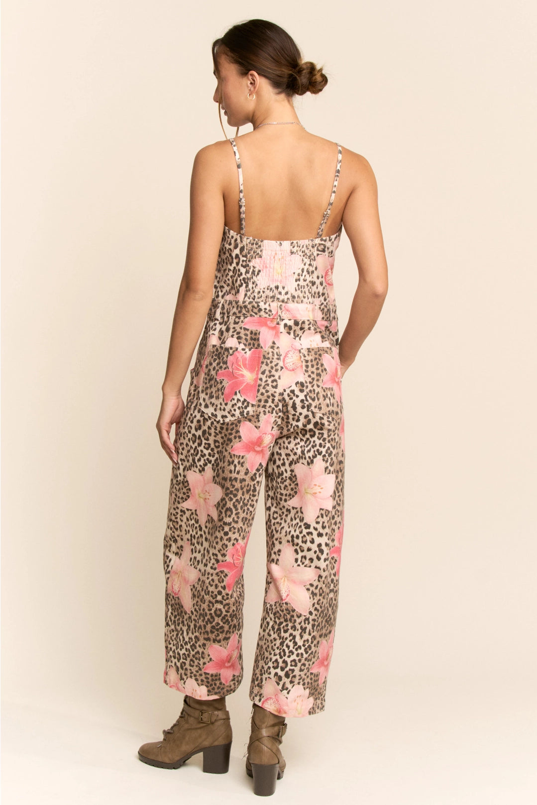 Woman wearing a floral and leopard print jumpsuit on a beige background