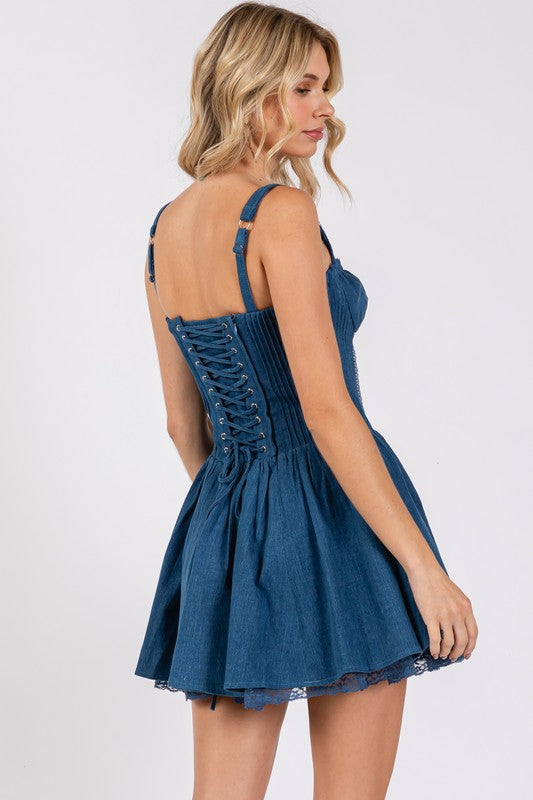 Back view of blue denim corset mini dress with adjustable straps, lace-up back, and flared skirt with lace-trim hem.