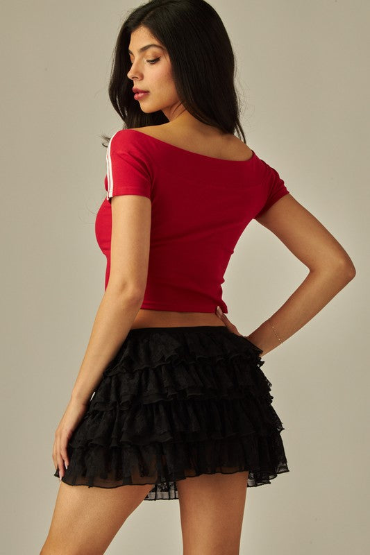 Back view of black lace tiered ruffle mini skirt with elastic waistband, styled with a red graphic crop top.