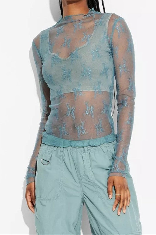 Sheer blue lace mesh long-sleeve top layered over a white bralette, styled with distressed low-rise jeans.